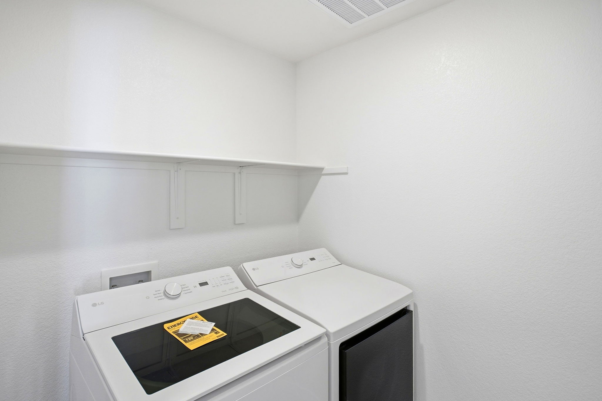 A white wall with a white shelf and a white wall with a black and yellow box and a.