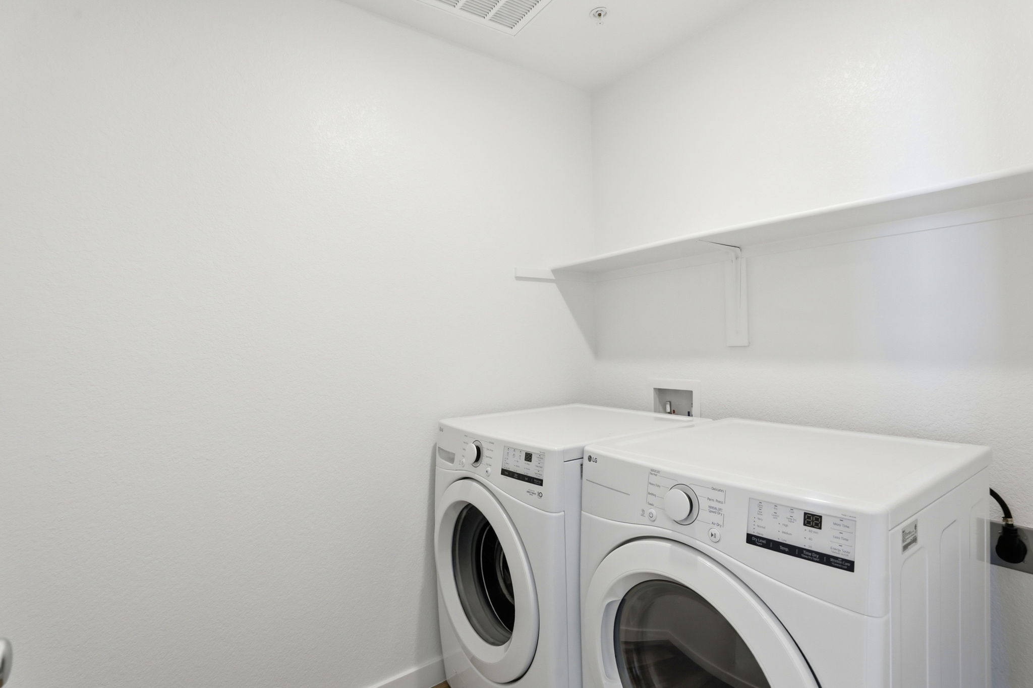A white room with a washing machine and a dryer.