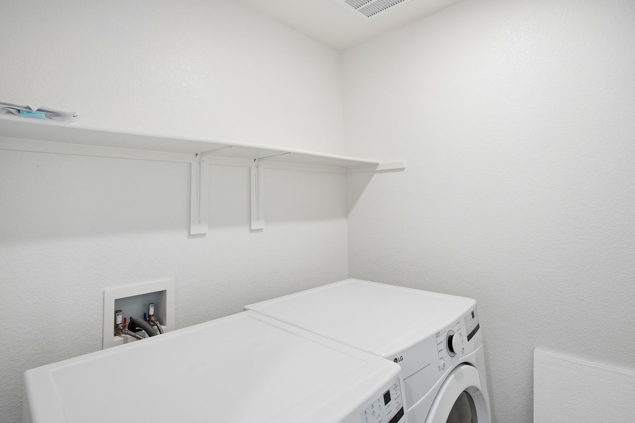 A white laundry room with a white shelf and a white radiator.
