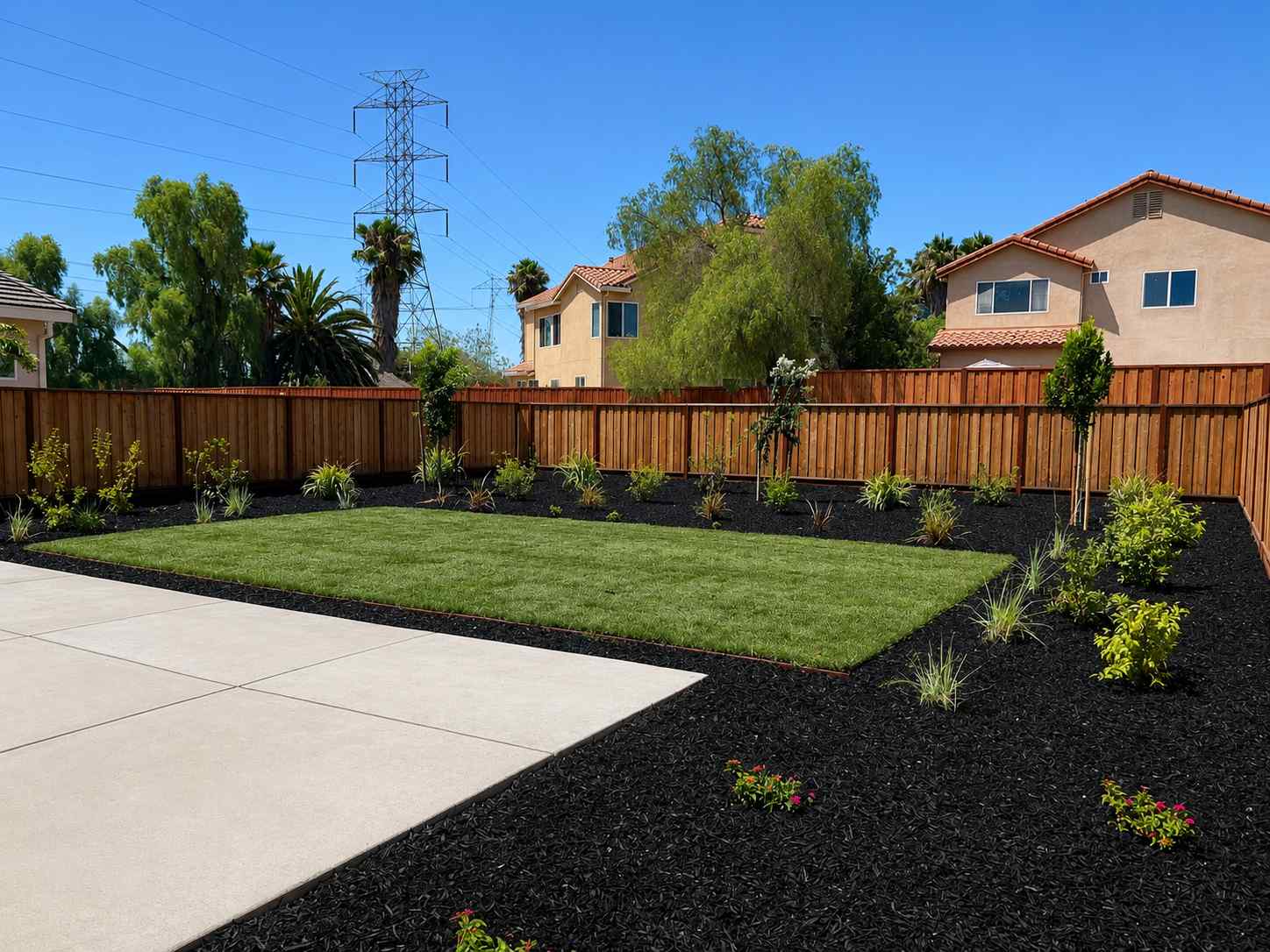 A backyard with a fence and a lawn with a brick path.