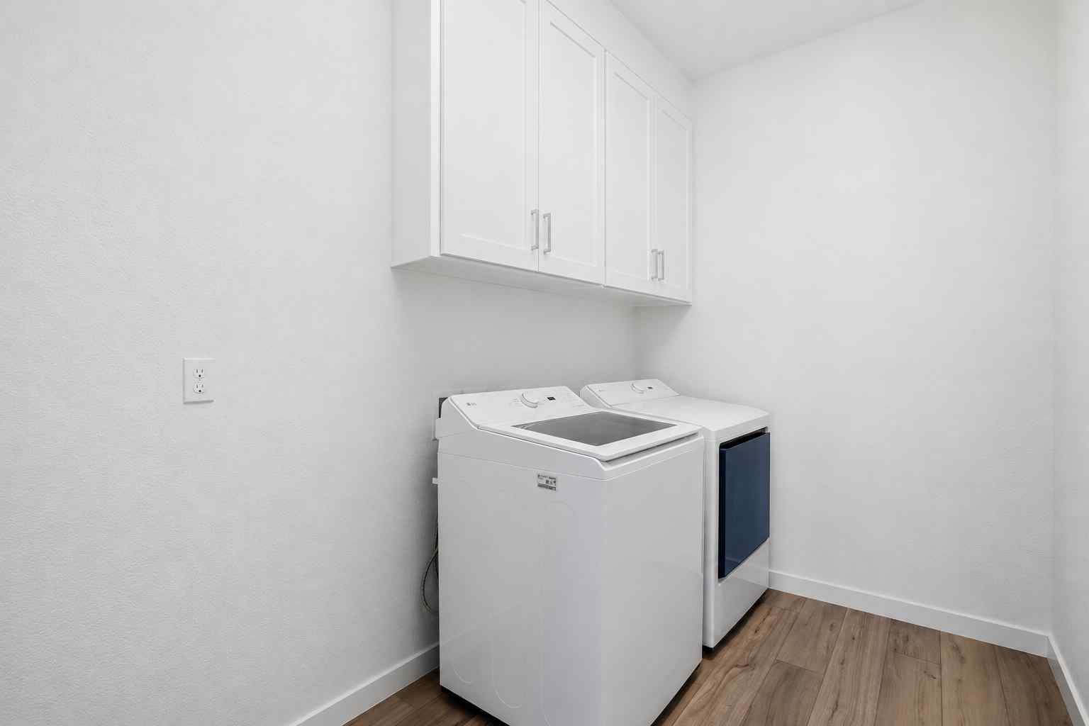 A white laundry room with white cabinets.