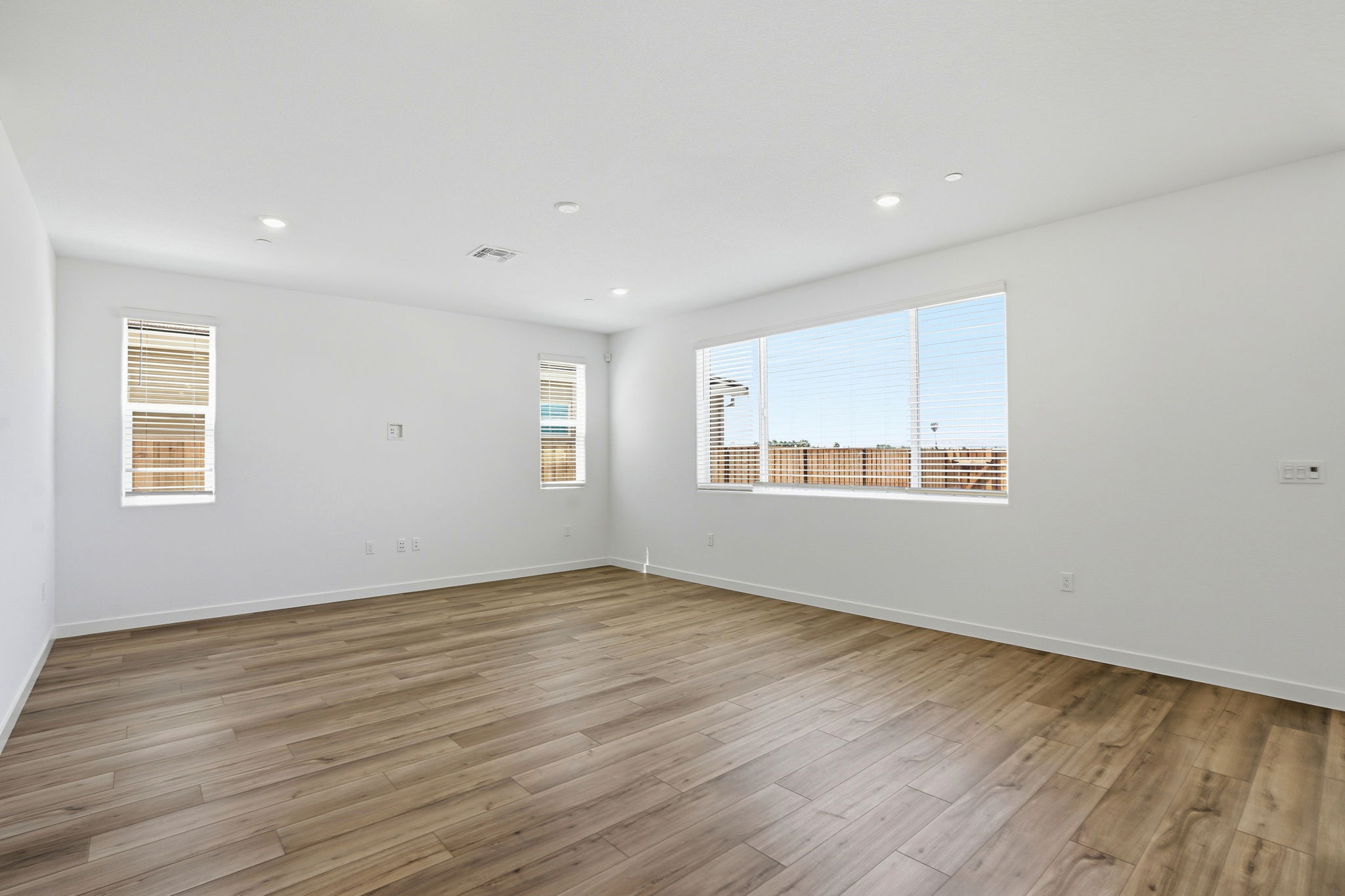 A room with a wood floor and a window with blinds.