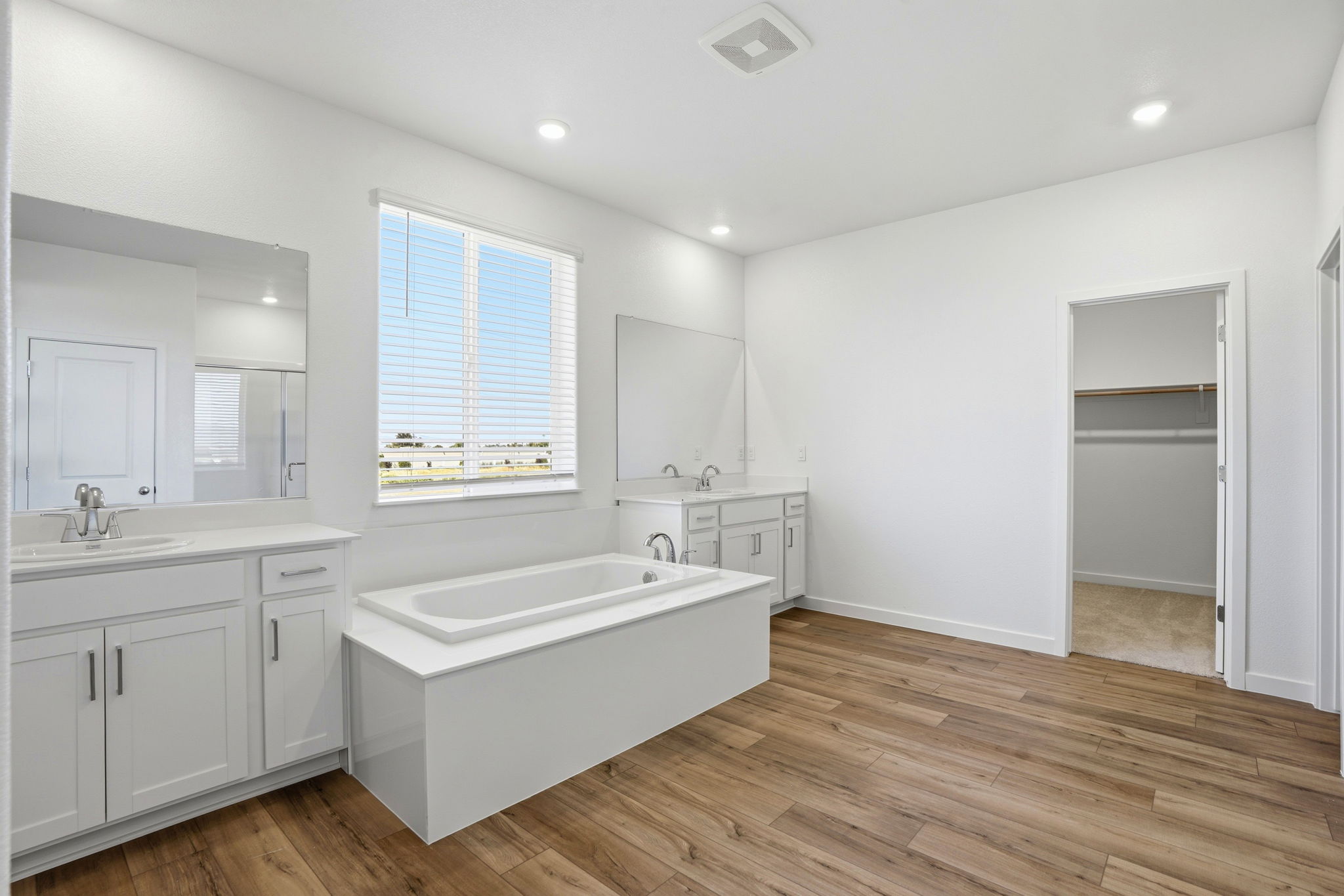 A bathroom with a tub sink and cabinets.