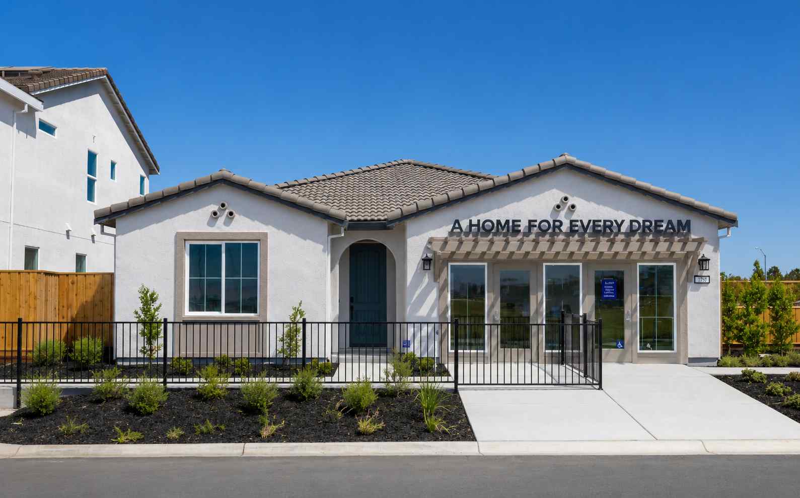 A white building with a black fence.