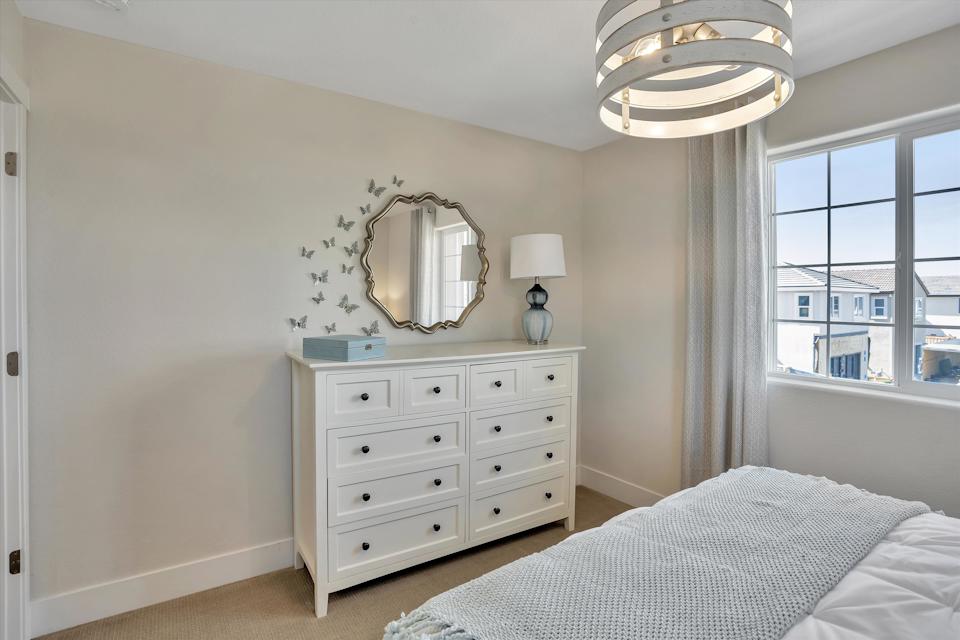 A bedroom with a mirror and a bed.