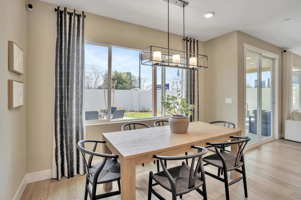 A dining room table with chairs and a chandelier above it.