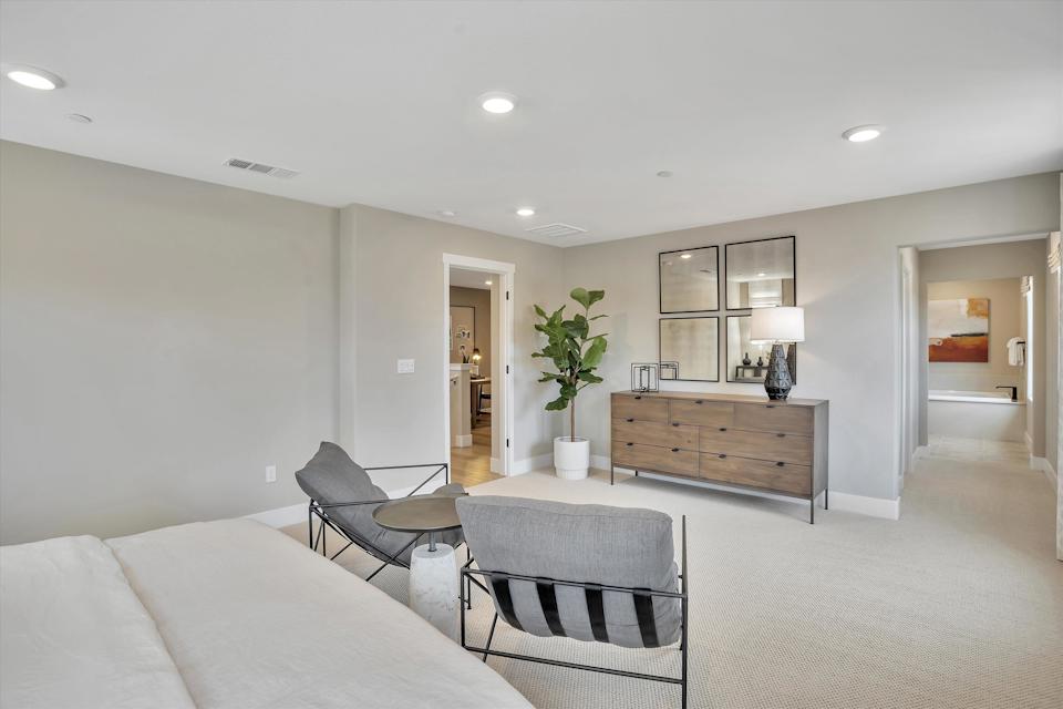 A room with a bed and chairs.