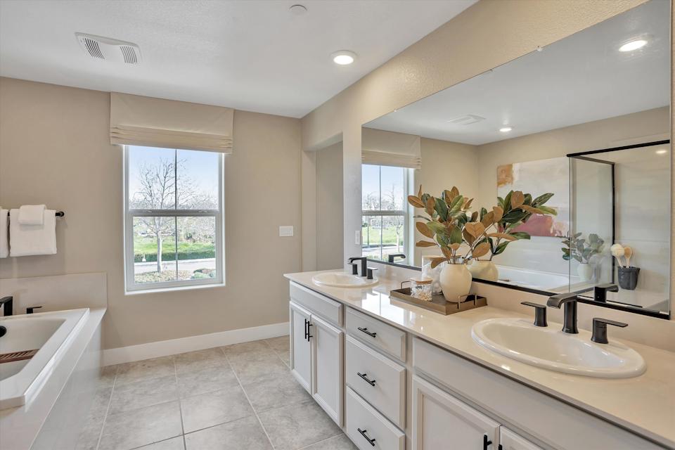 A bathroom with a tub sink and a large mirror.
