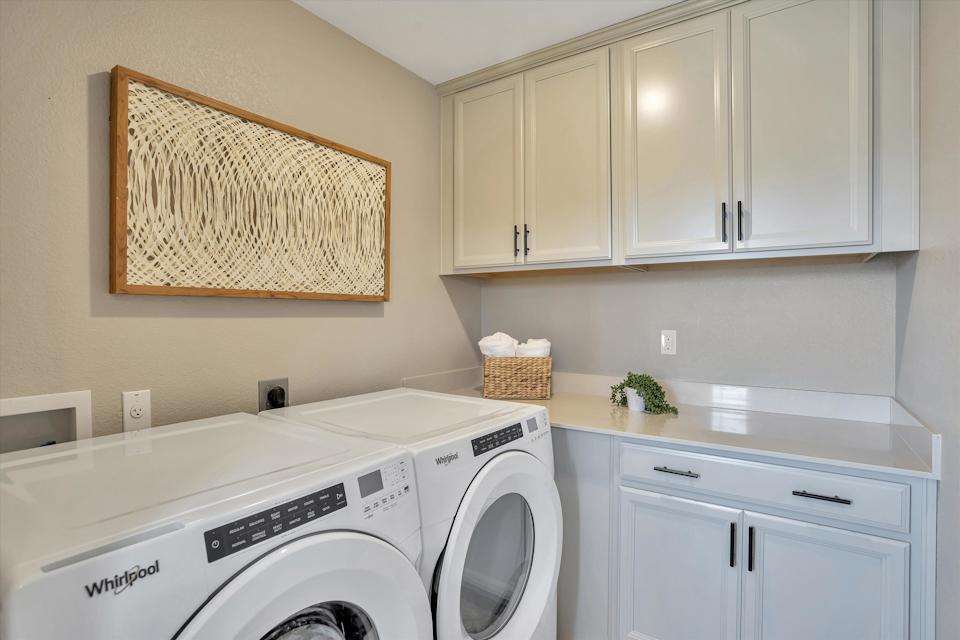A laundry room with white cabinets.