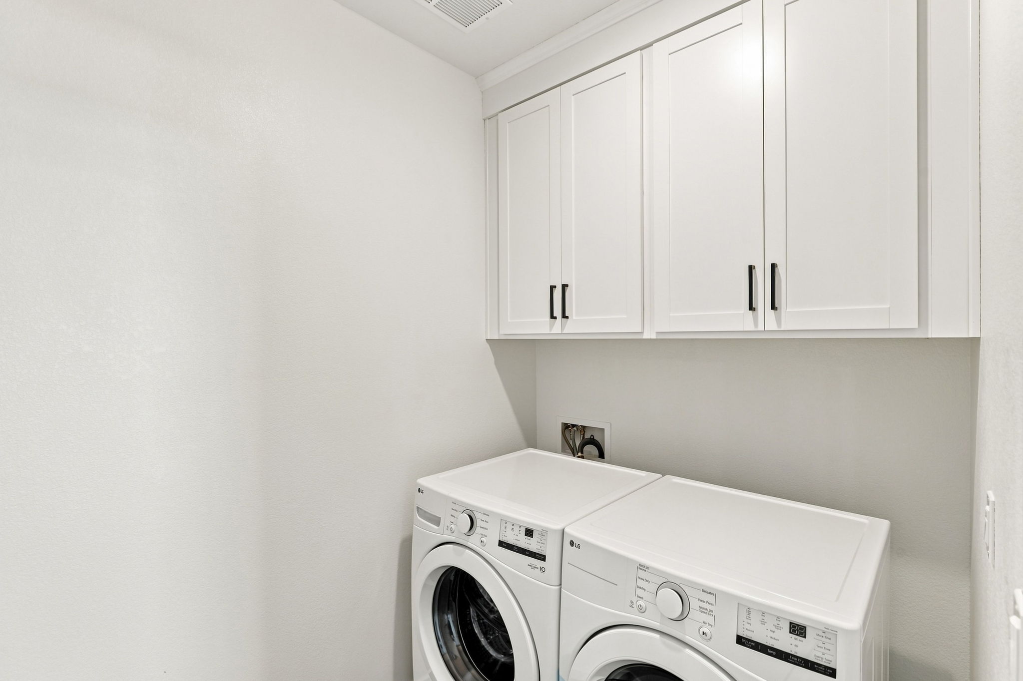 A white laundry room with white cabinets.