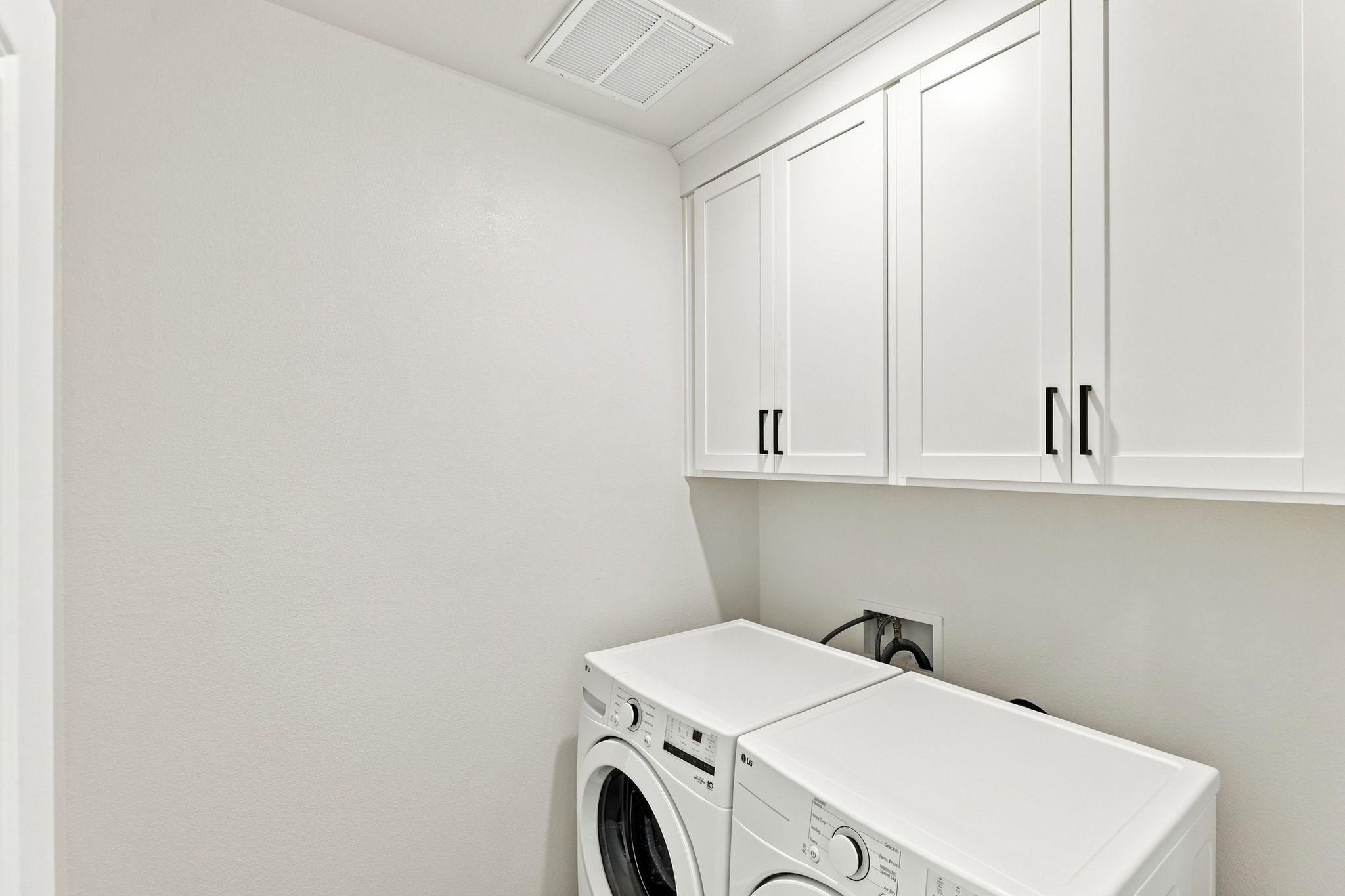 A white laundry room with white cabinets.