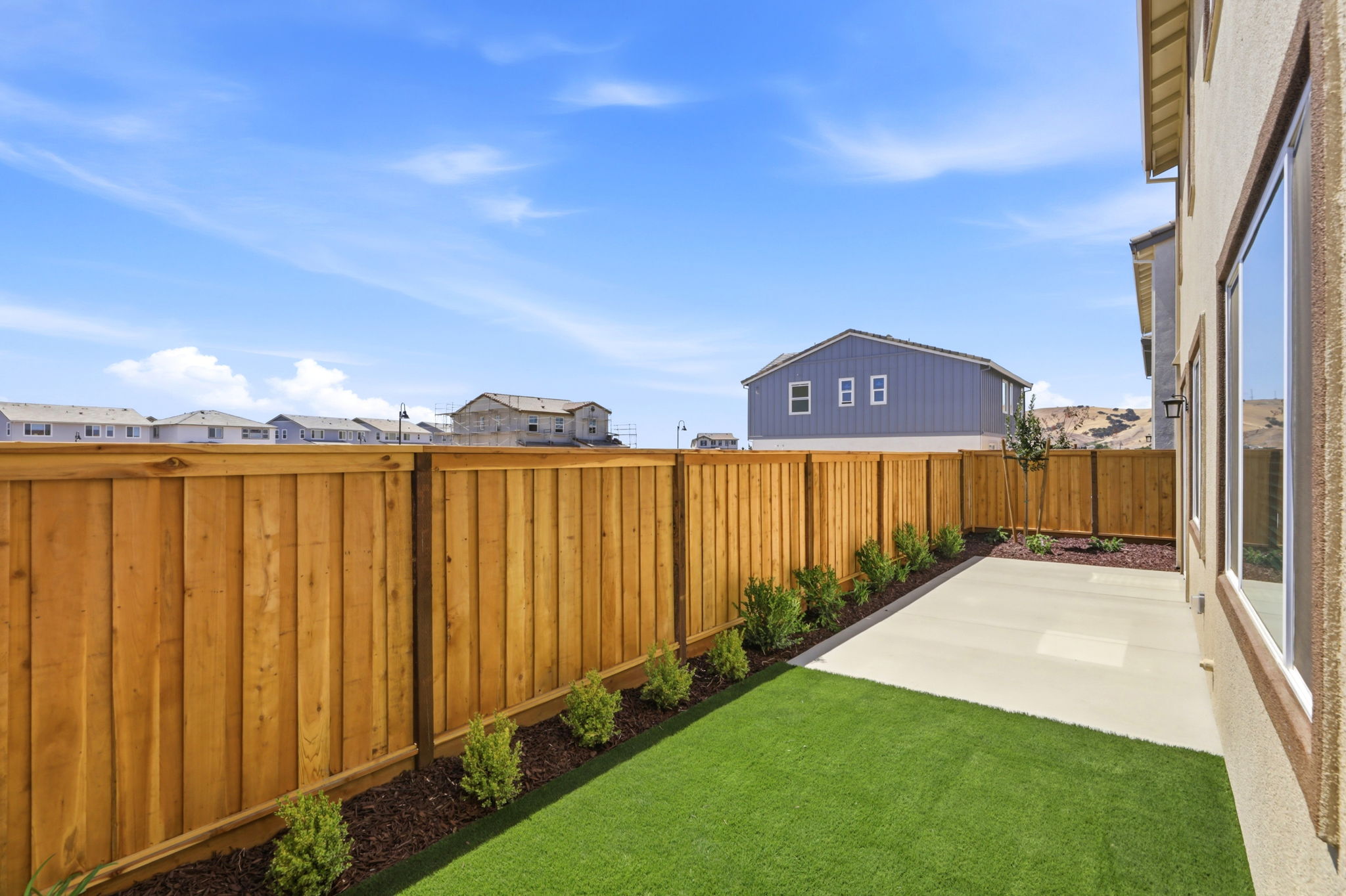 A fenced in yard with a house and a grass yard.