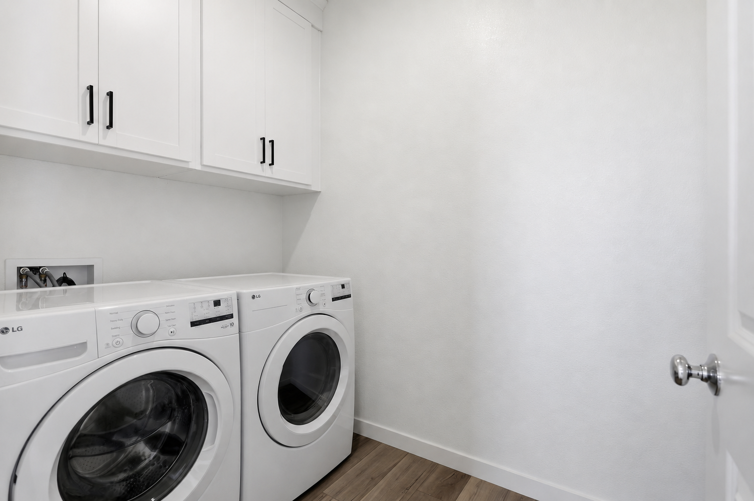 A white room with a washing machine and a dryer.