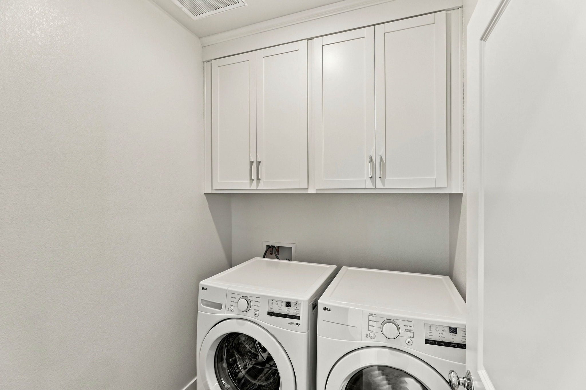 A white laundry room with white cabinets.