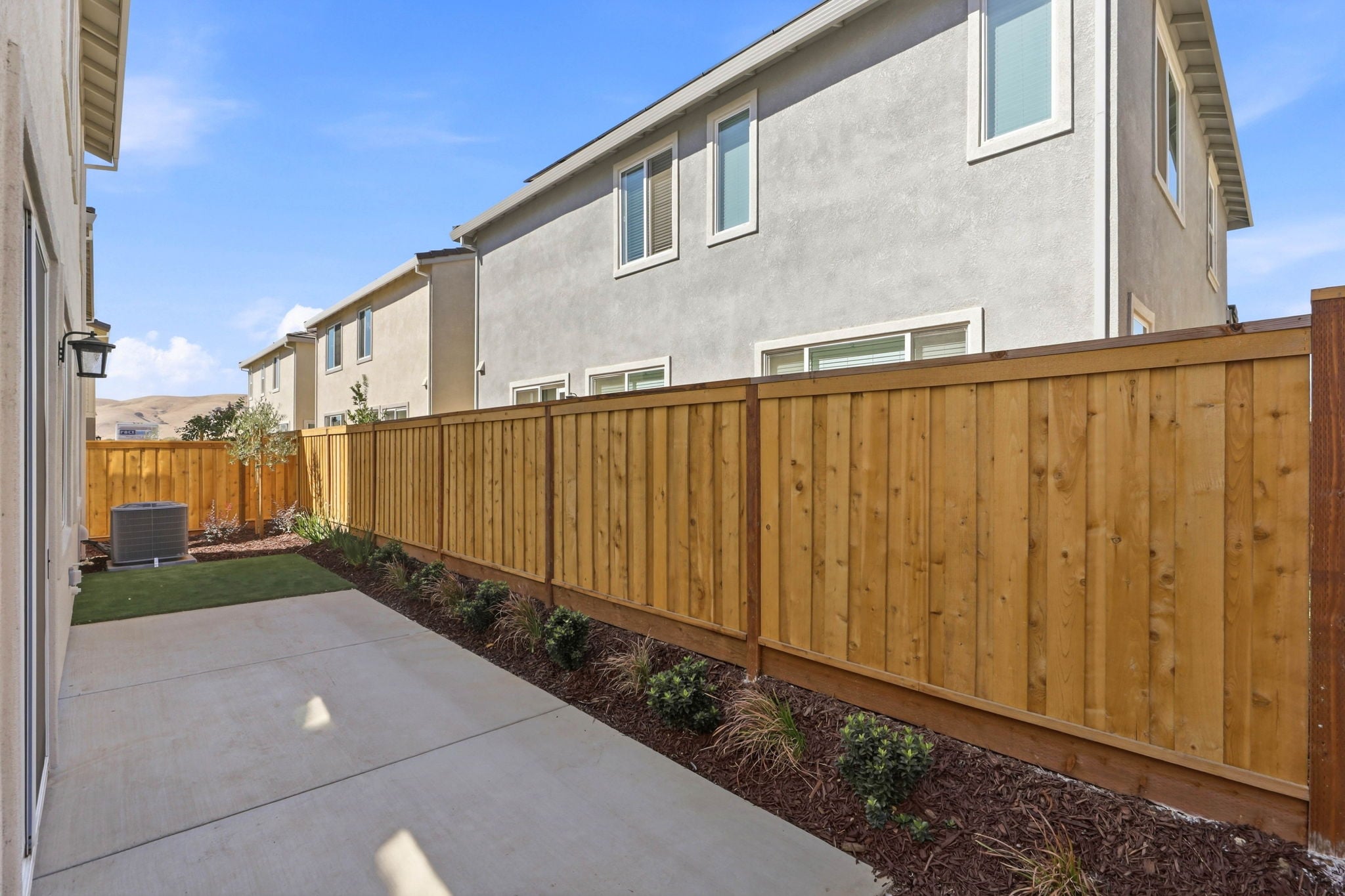 A fenced in yard with a house and a driveway.