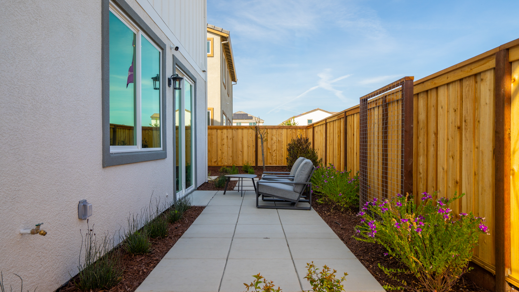 A patio with a bench and a fence and a building with a wood fence.