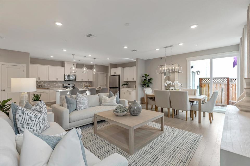 A large living room with a large chandelier and a dining table.