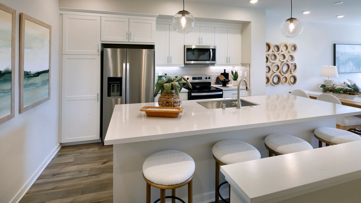 A kitchen with a bar stool and a white counter top.