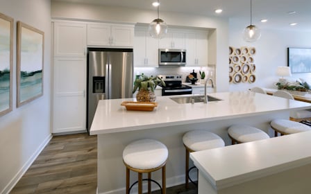 A kitchen with a bar stool and a white counter top.