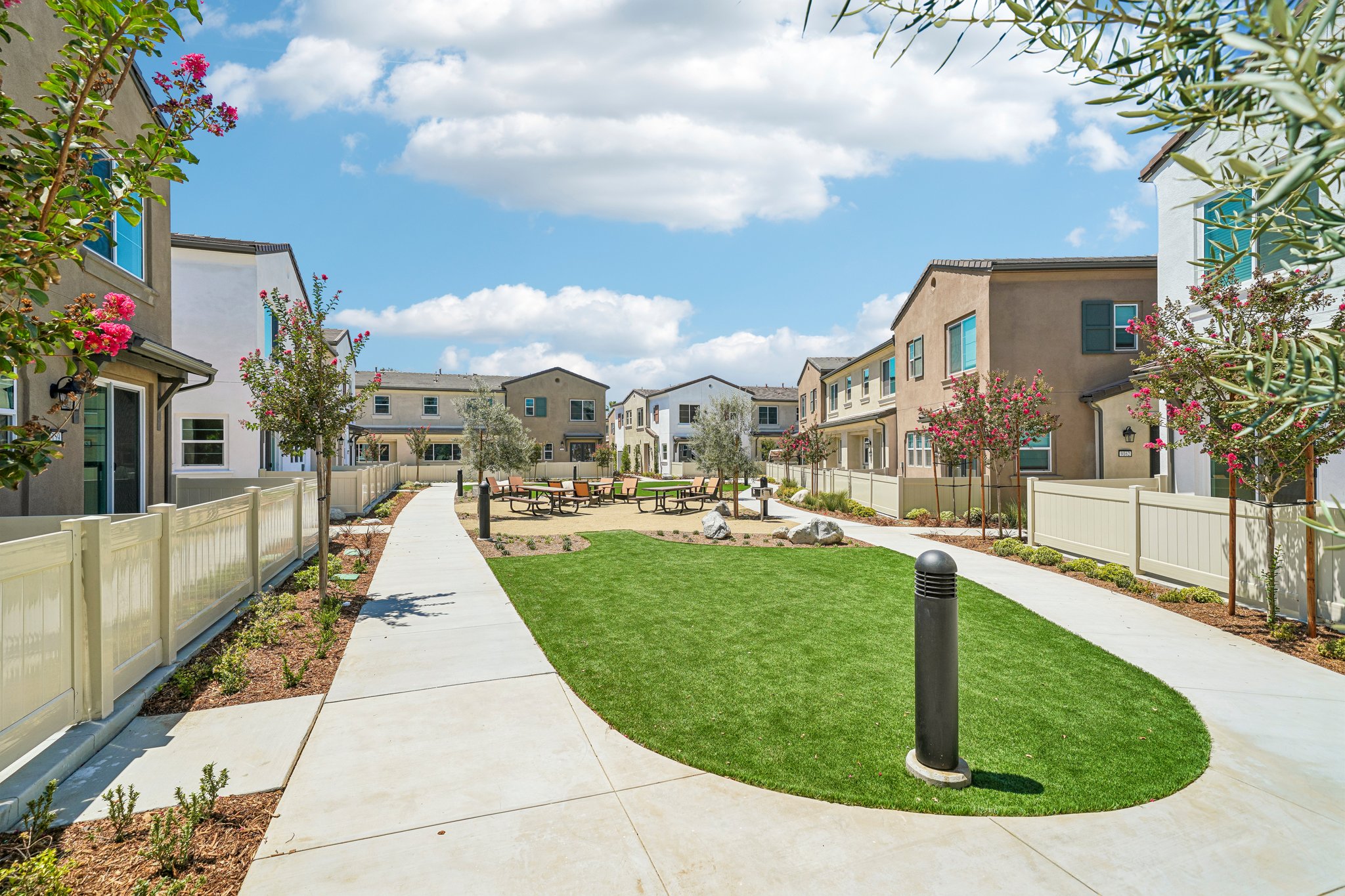 A sidewalk with grass and buildings.