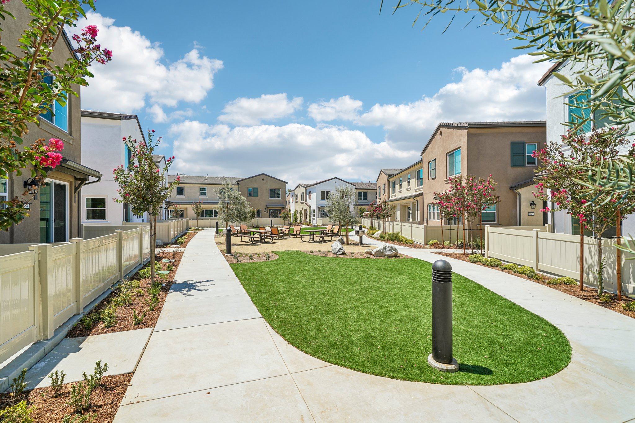 A sidewalk with grass and buildings.