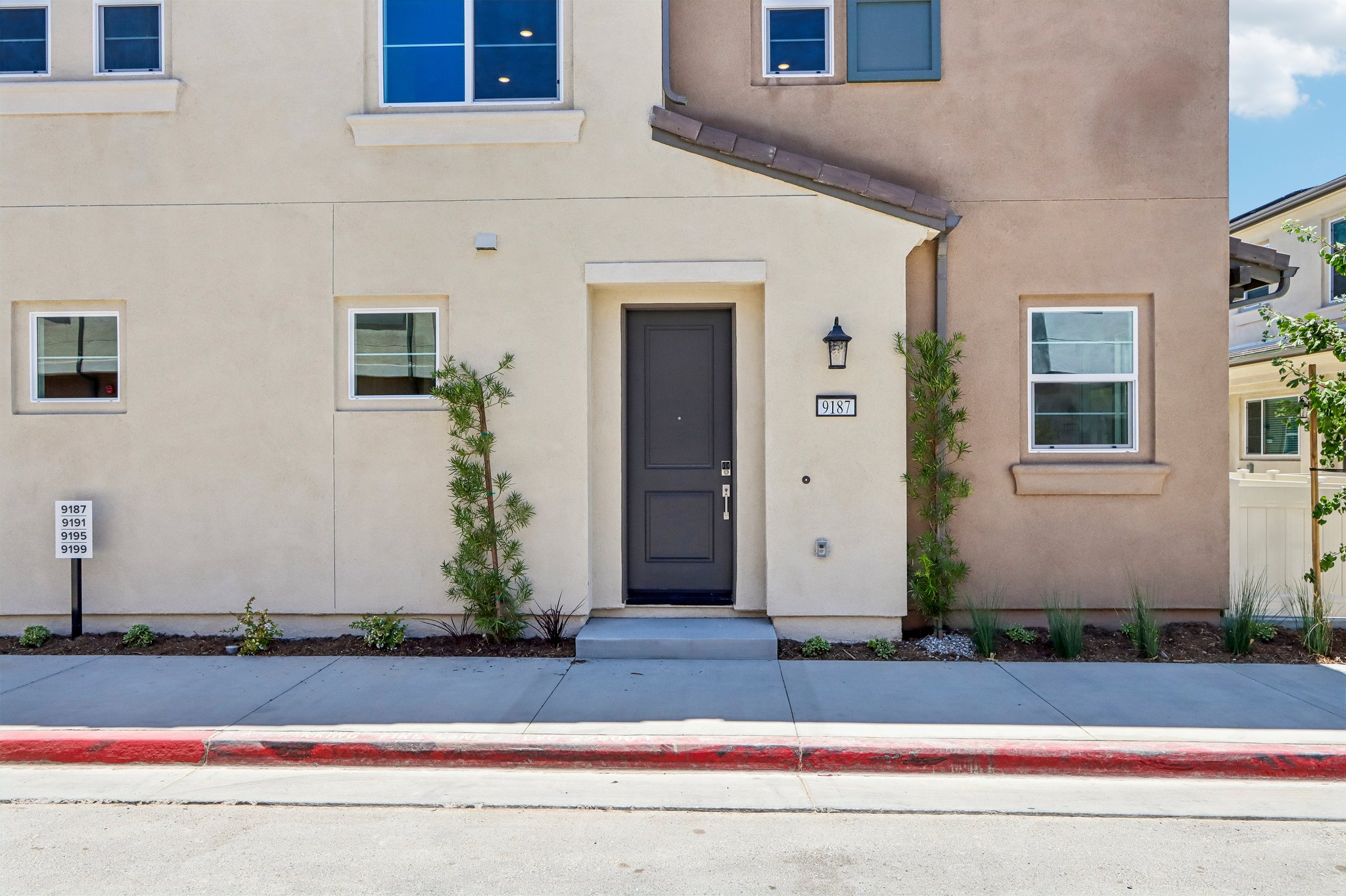 A building with a door and plants in front of it.