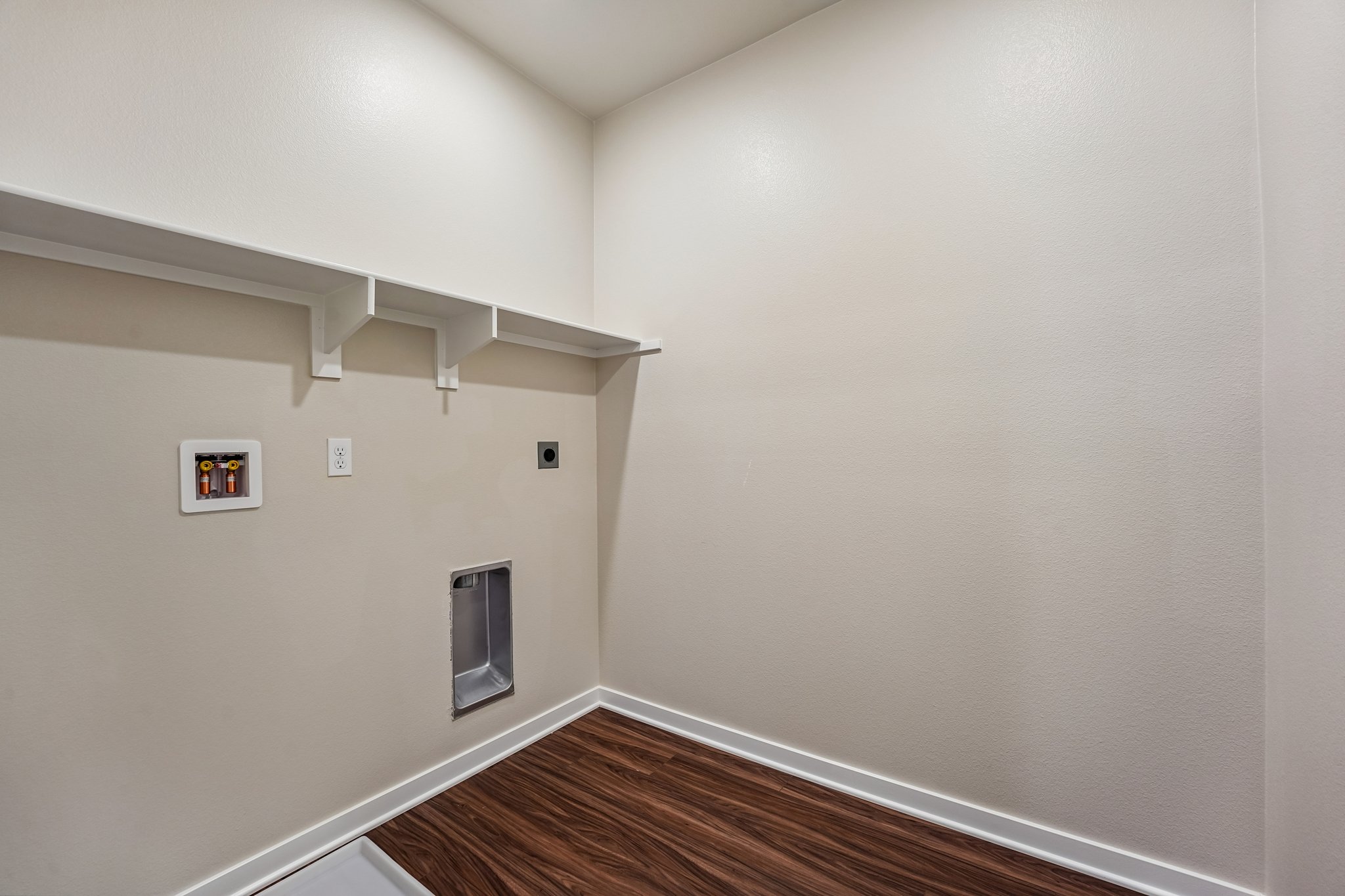 A room with a wood floor and a white wall with a light.