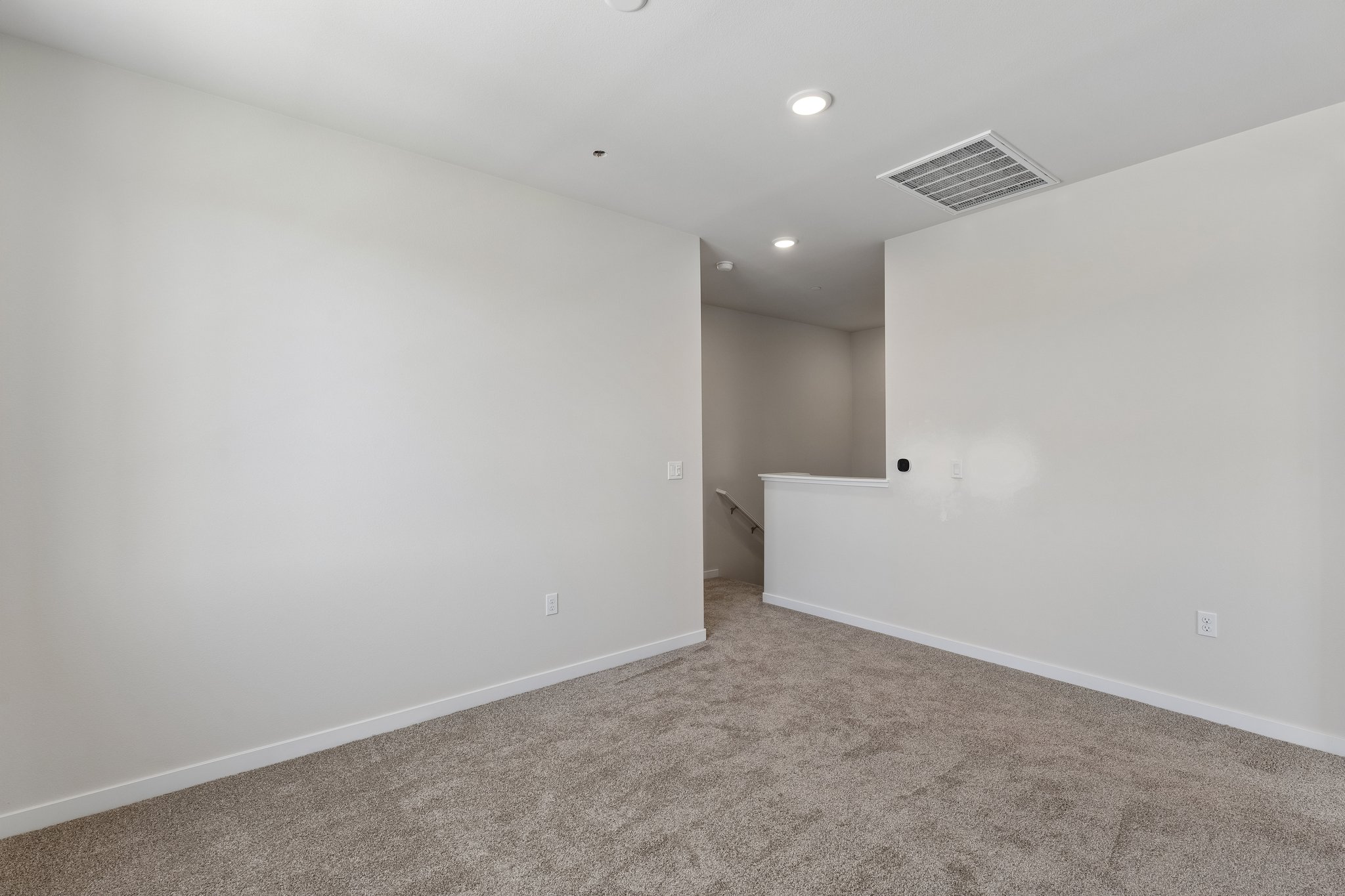 A room with a carpet and a white wall.