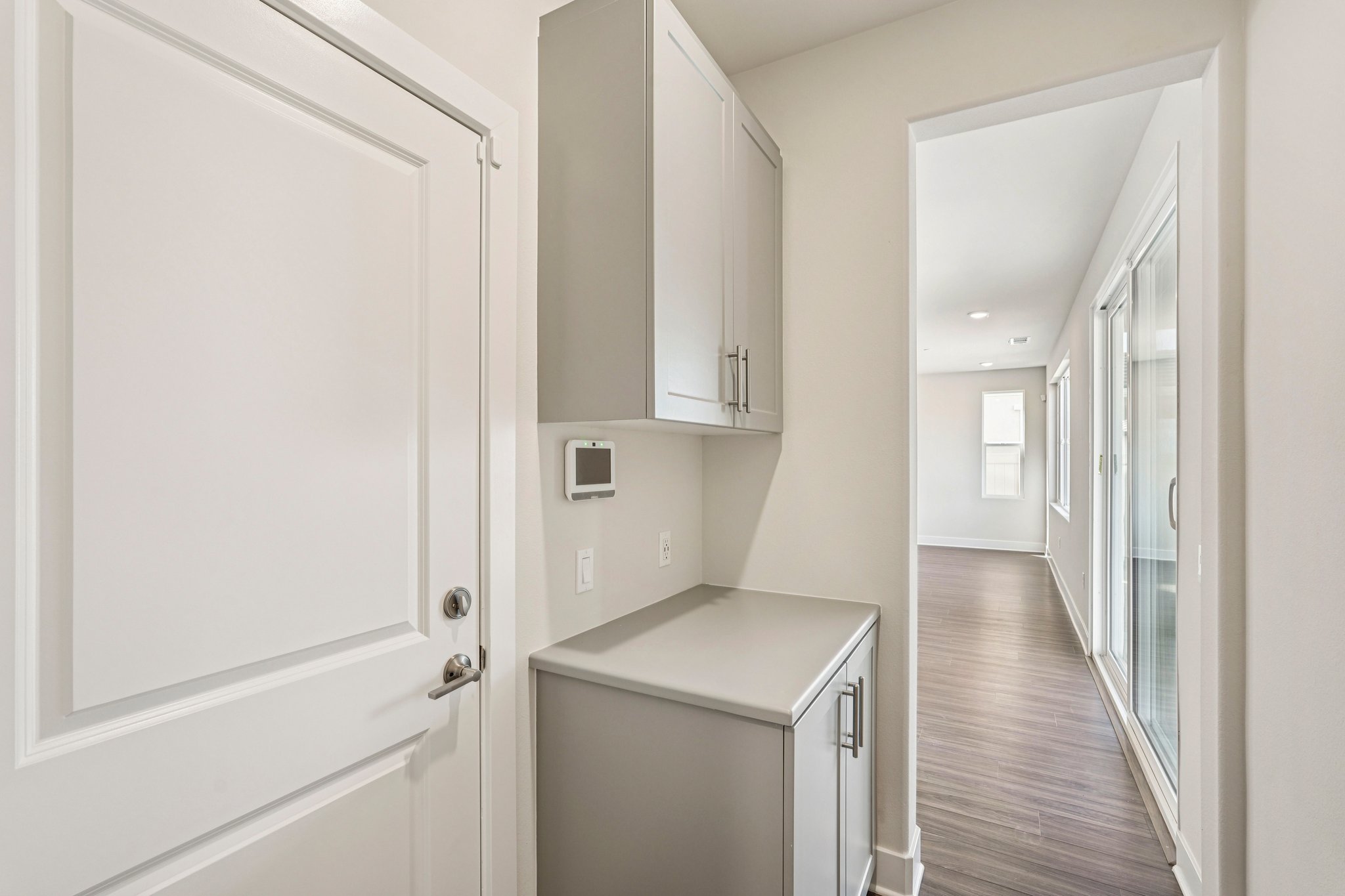 A hallway with white cabinets.