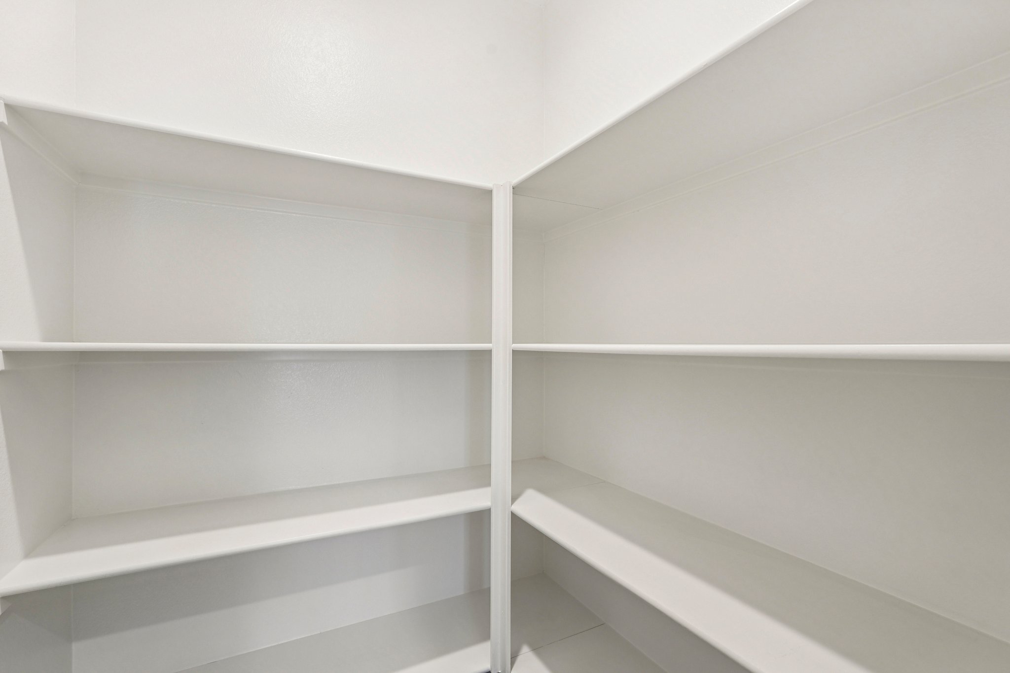 A white shelf with white walls.