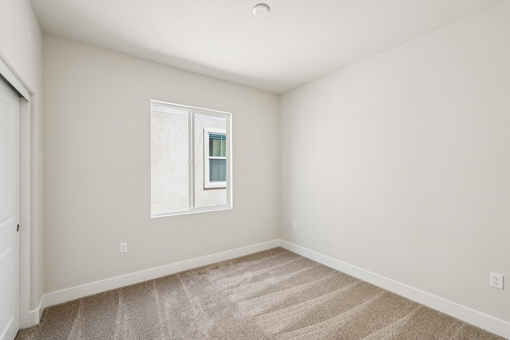 A room with a window and a rug.