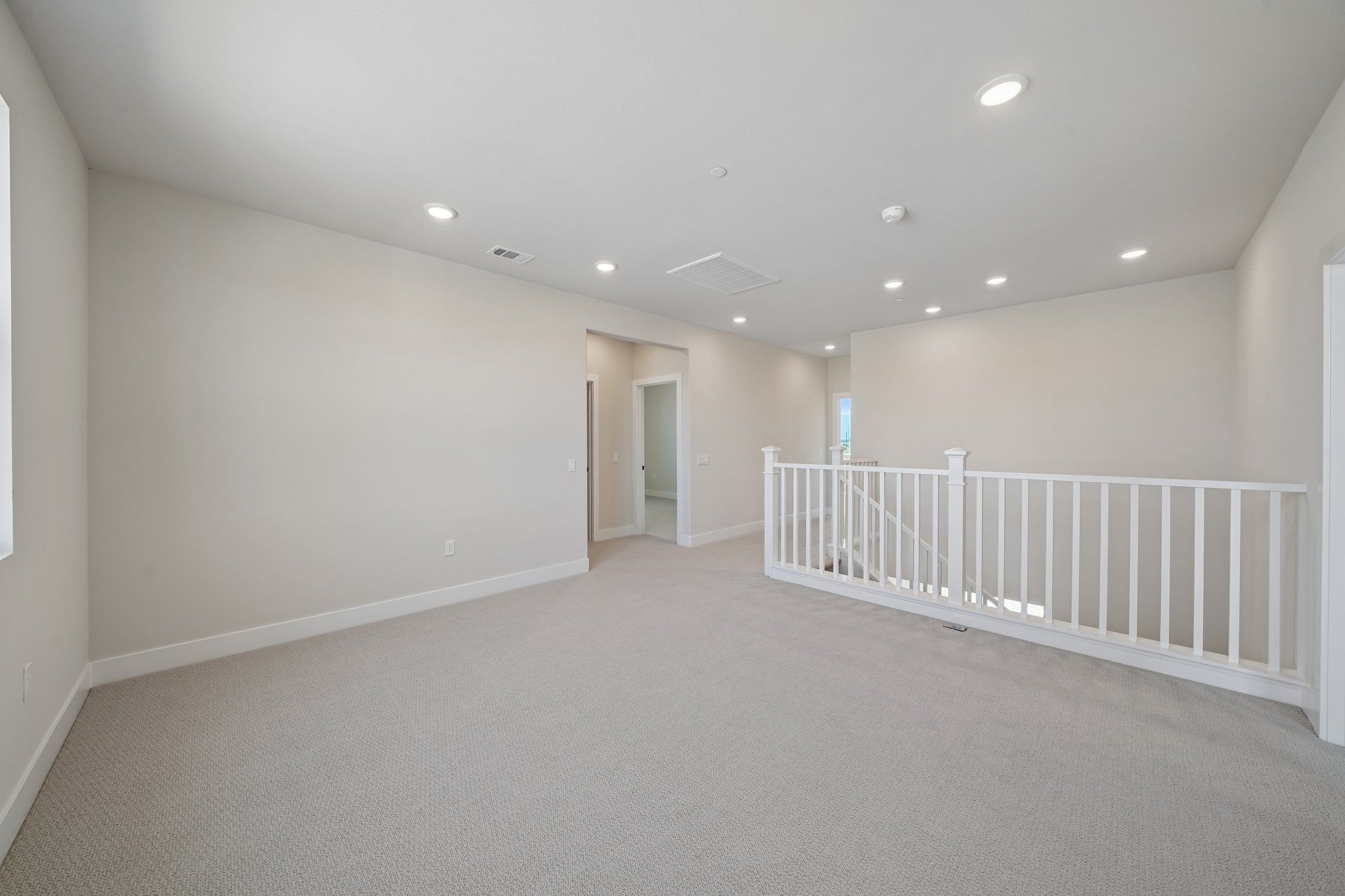 A long white hallway with white railings.