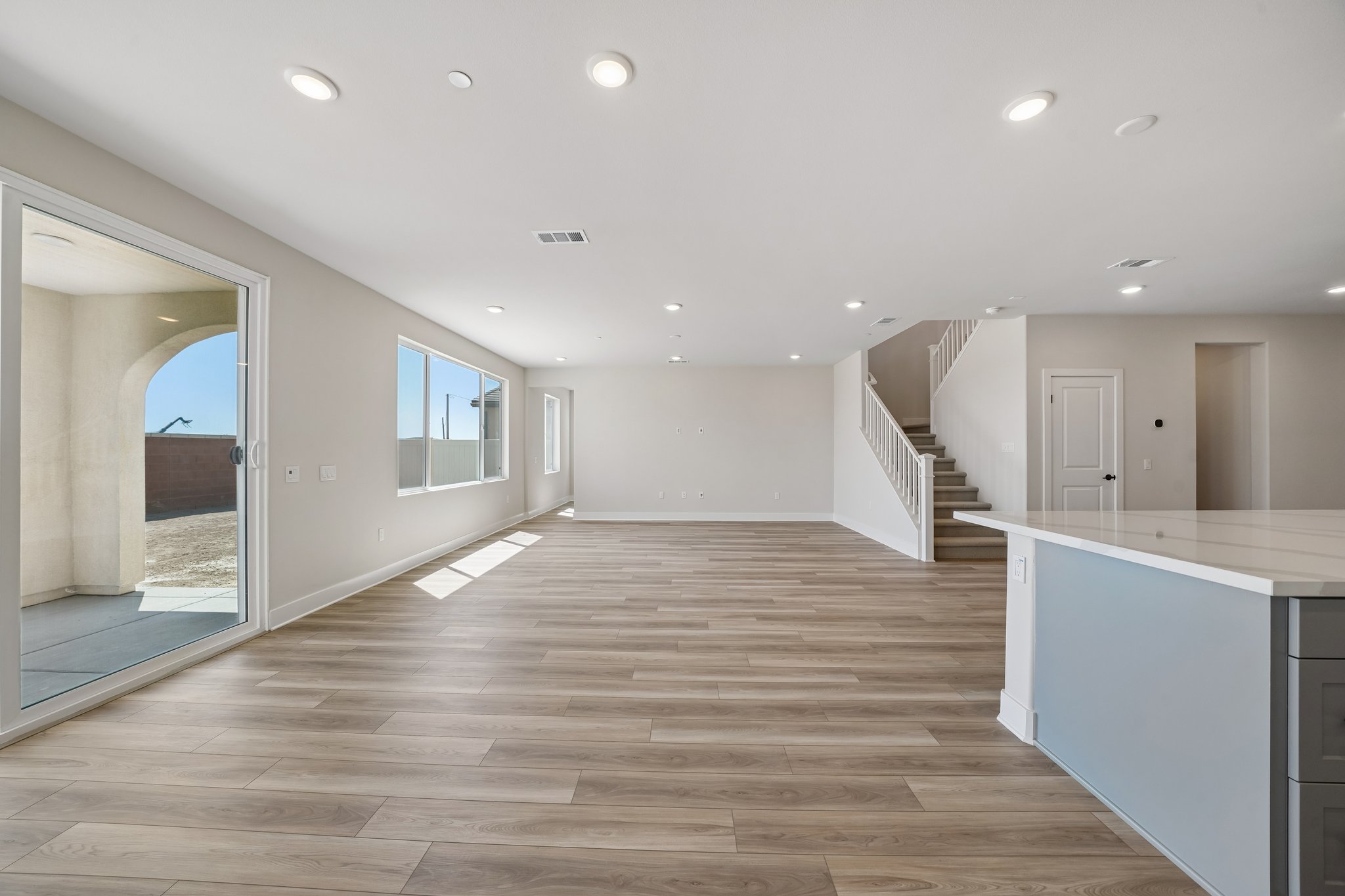 A large empty room with a wood floor and a glass wall.
