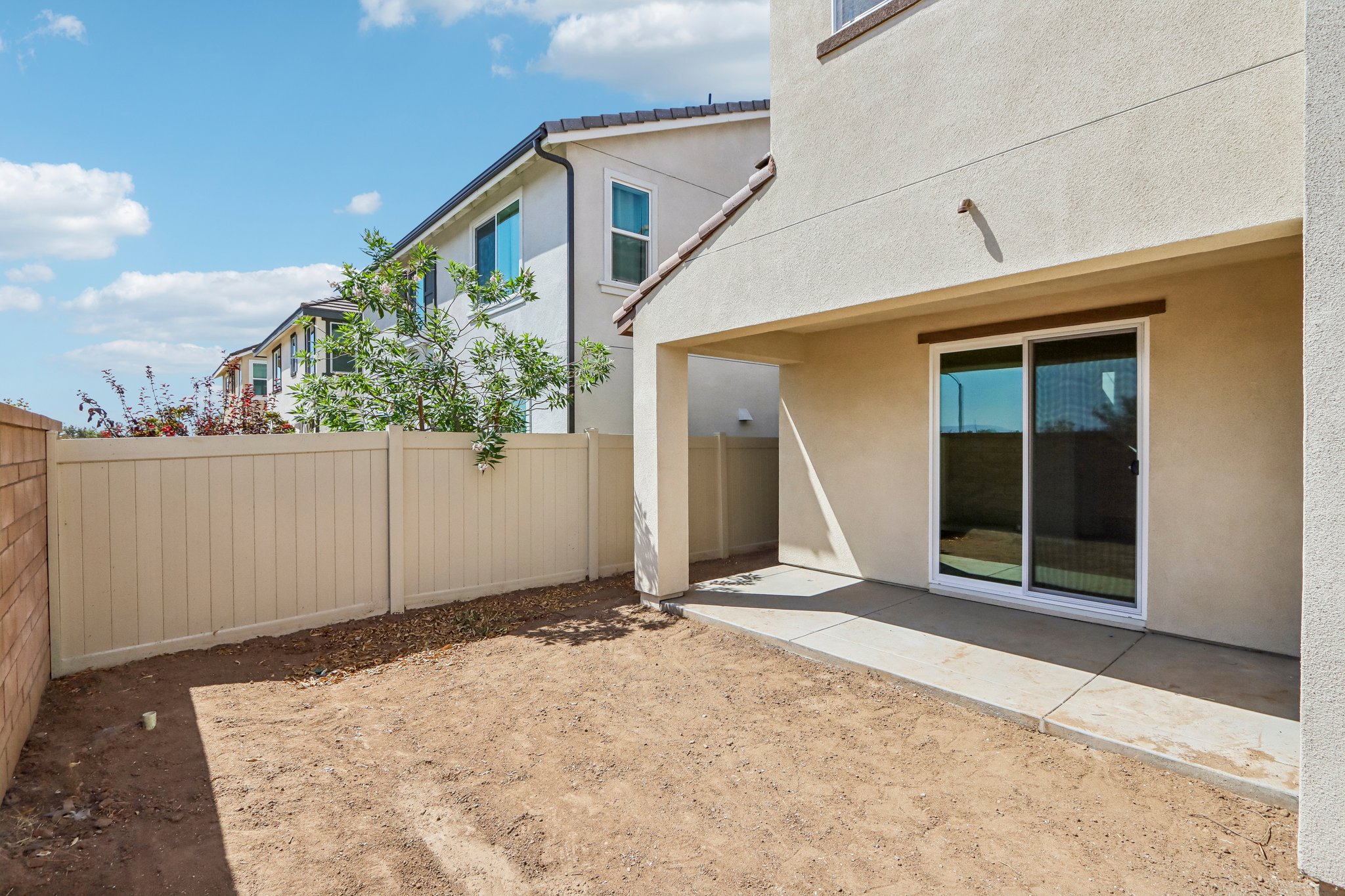 A house with a fence and a dirt yard.