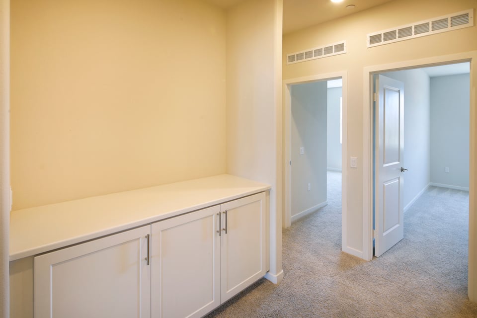 A hallway with white cabinets.