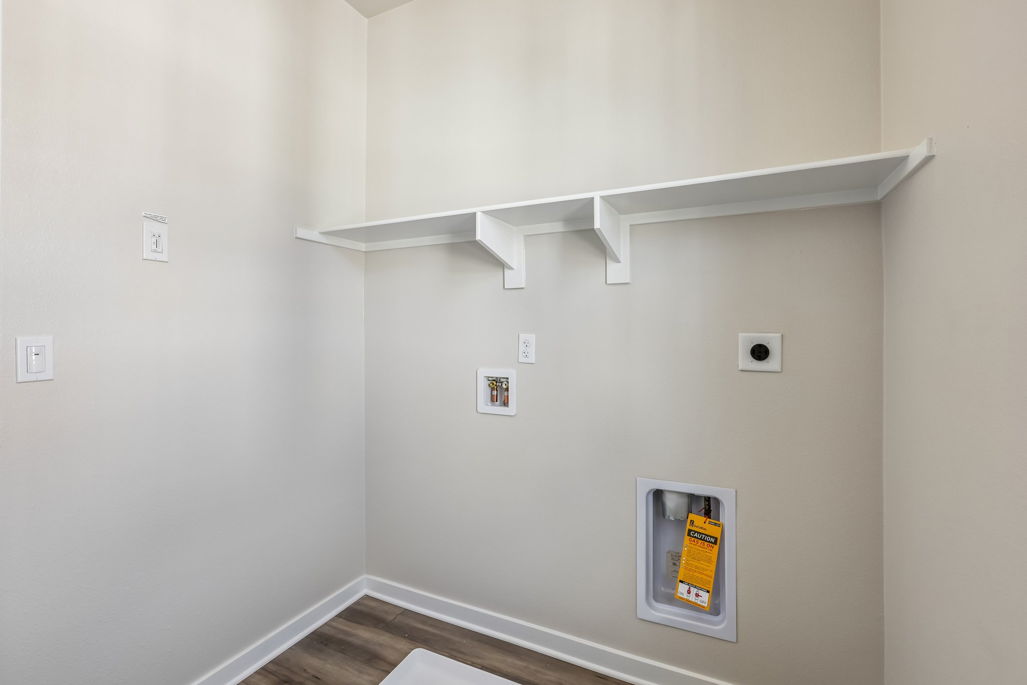 A white wall with a vent and a light switch.