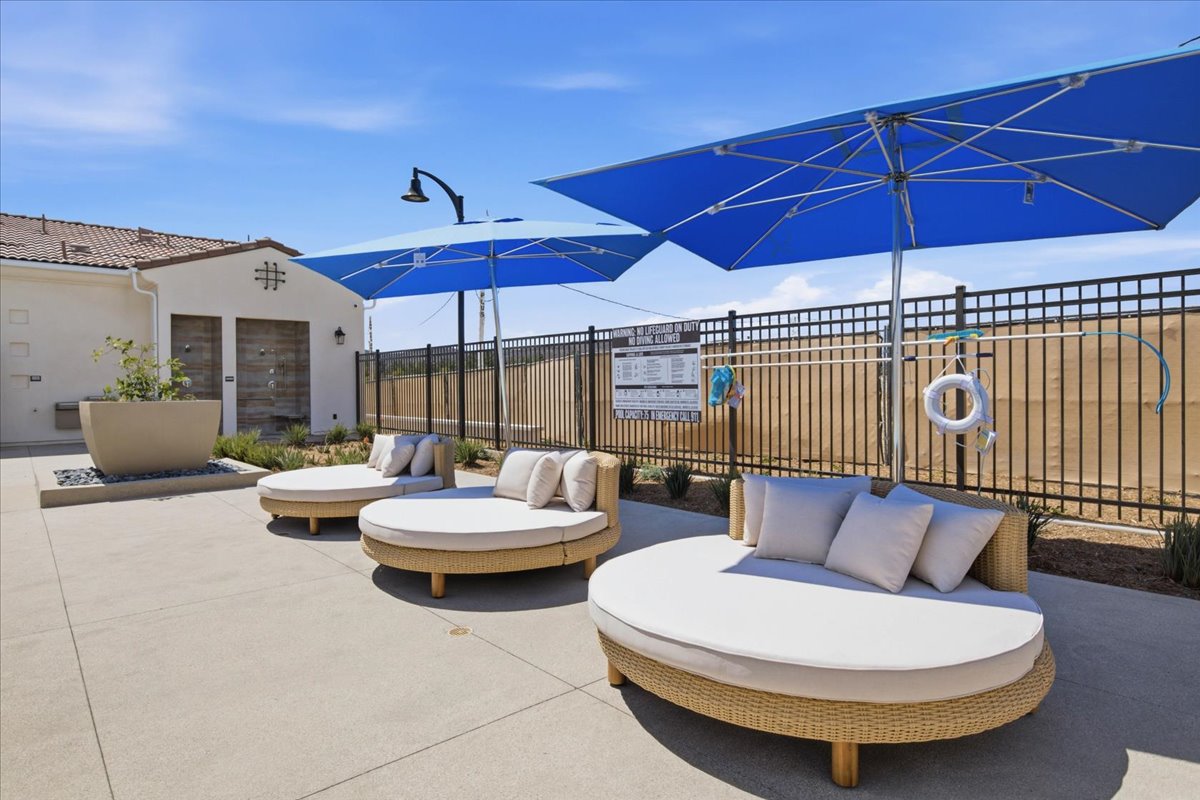 A patio with a couple of lounge chairs and umbrellas.