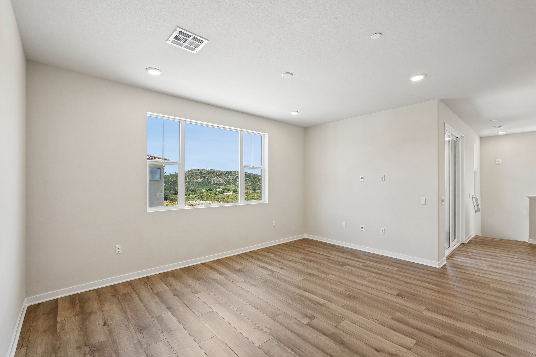 A room with a wood floor and a window with a view of trees.