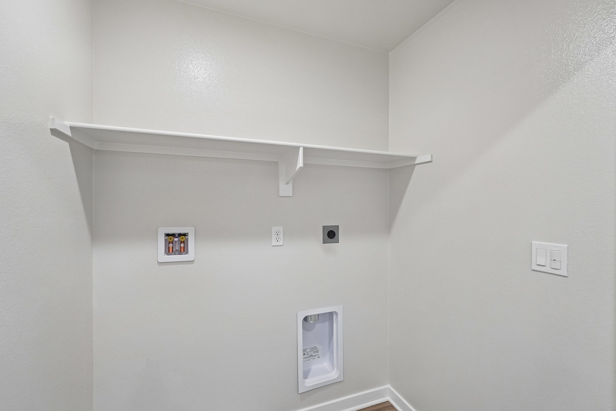 A white wall with a light switch.
