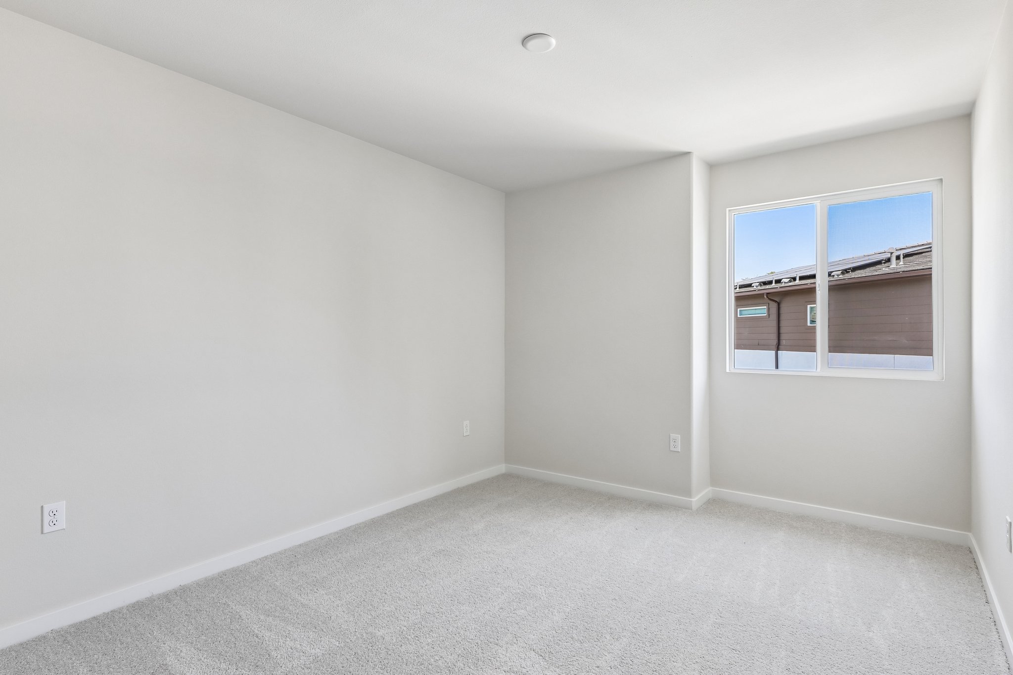 A room with a window and a white wall.