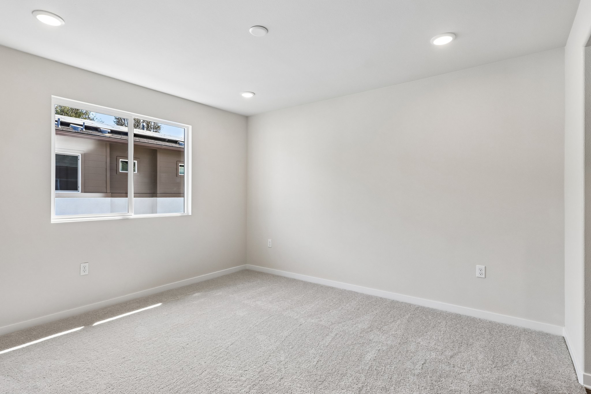 A room with a window and a white wall.