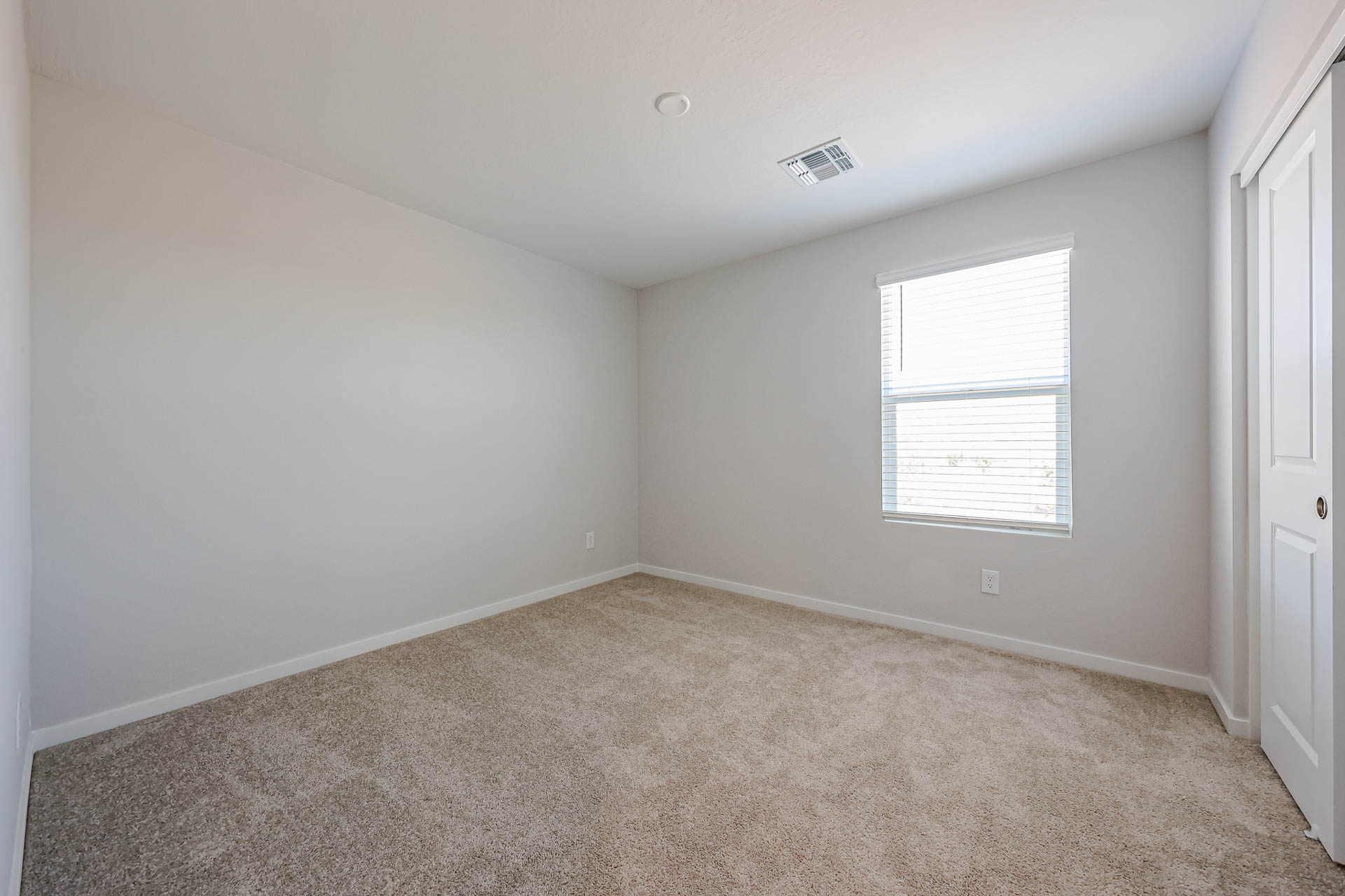 A room with a carpet and a window.