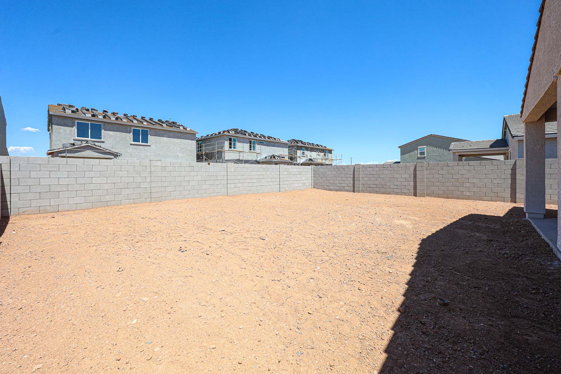 A dirt road with a wall and buildings on the side.