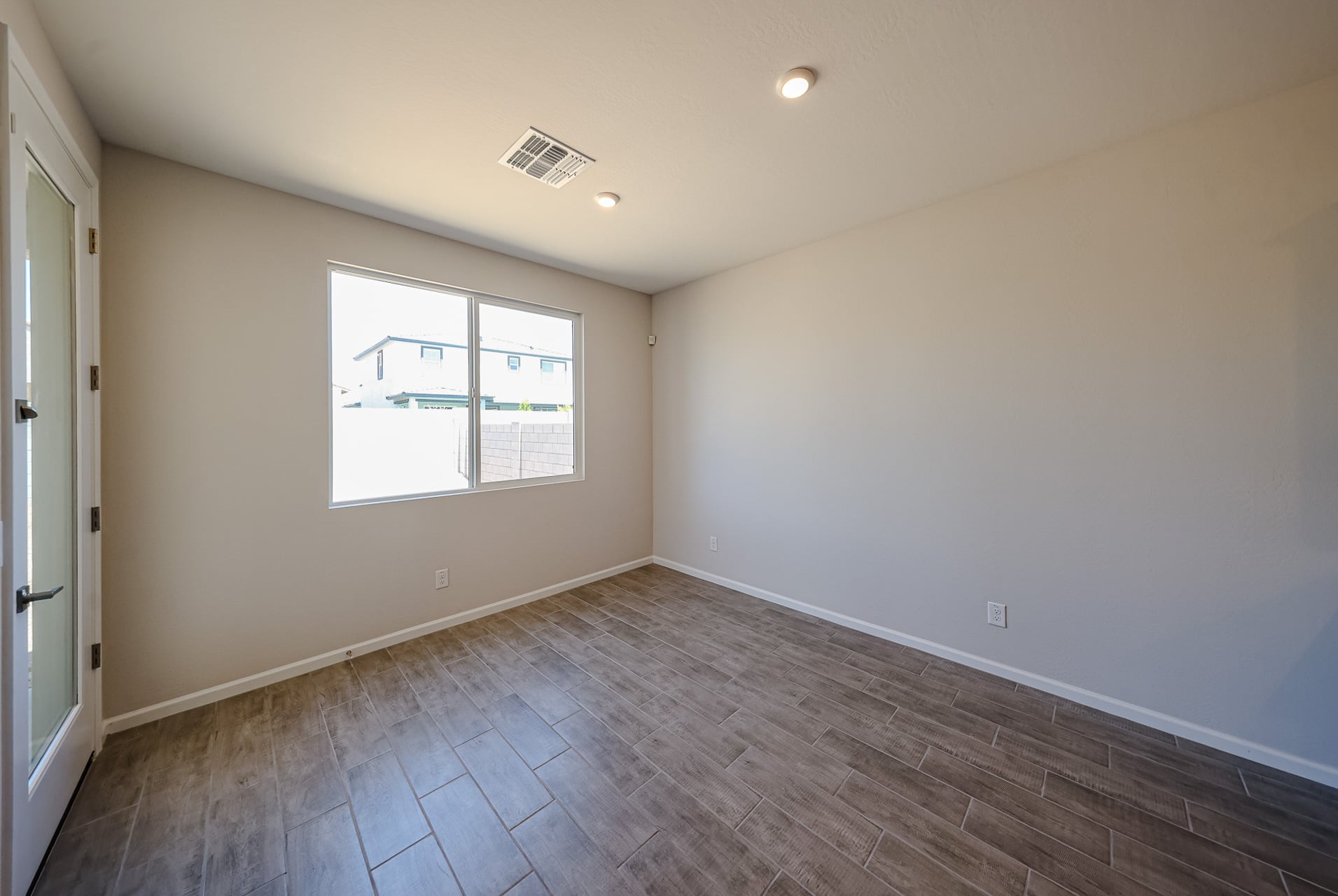A room with a wood floor and a window with blinds.