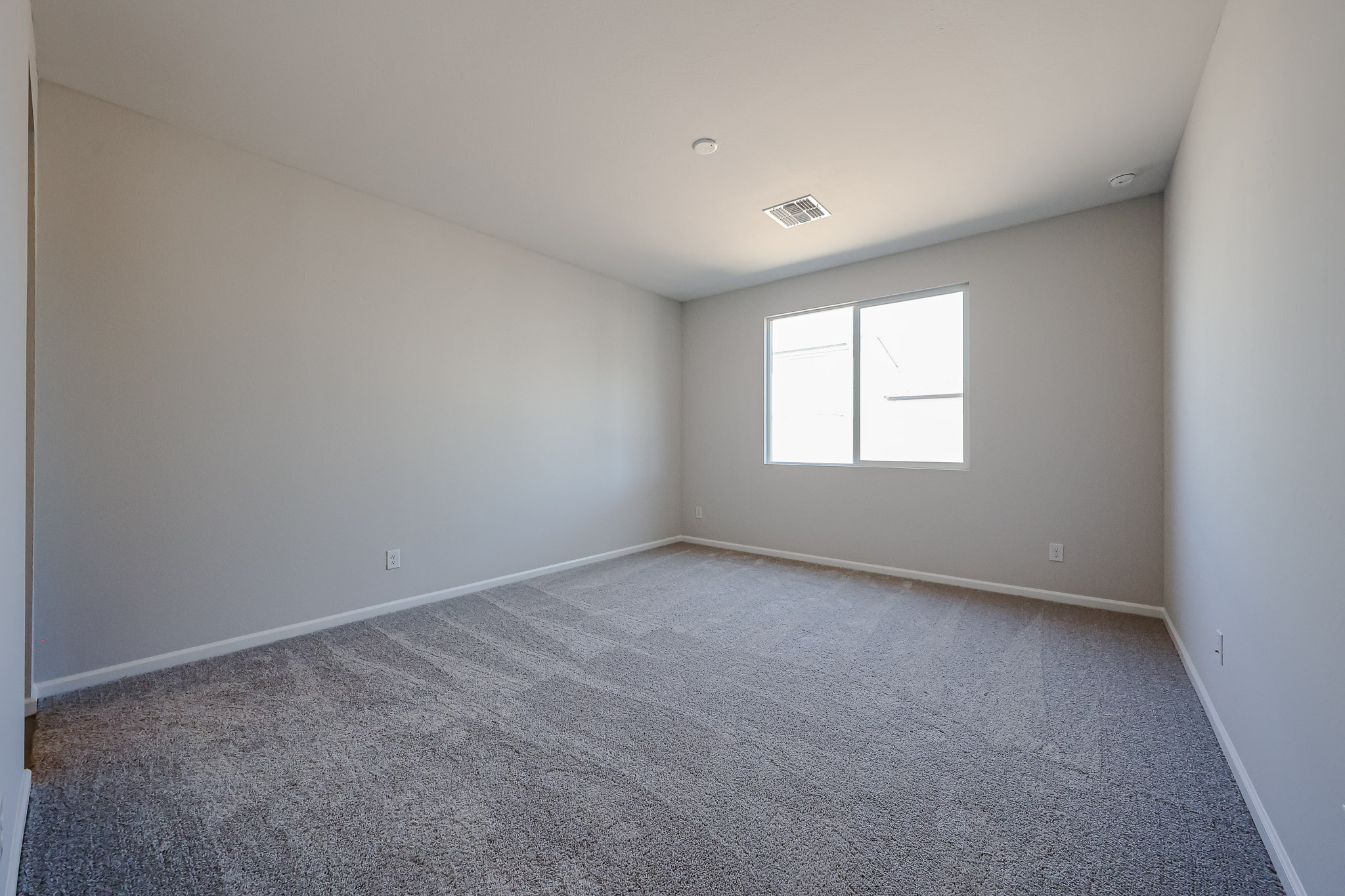 A room with a carpet and a window.