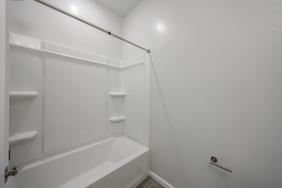 A bathroom with a shower unit and toilet.
