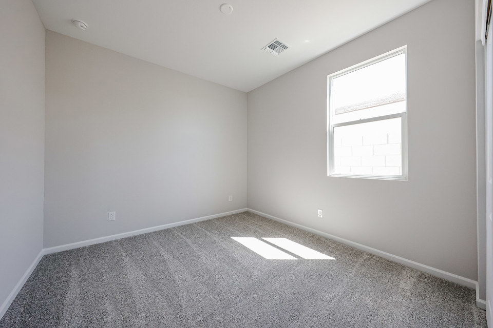 A room with a window and a rug.