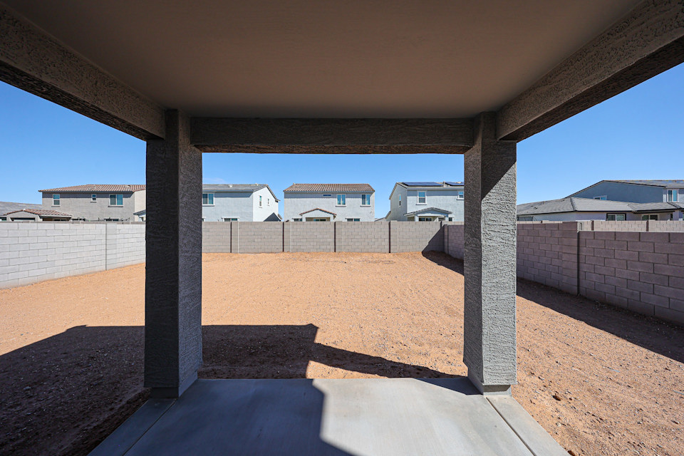A concrete wall with a fence and buildings in the background.