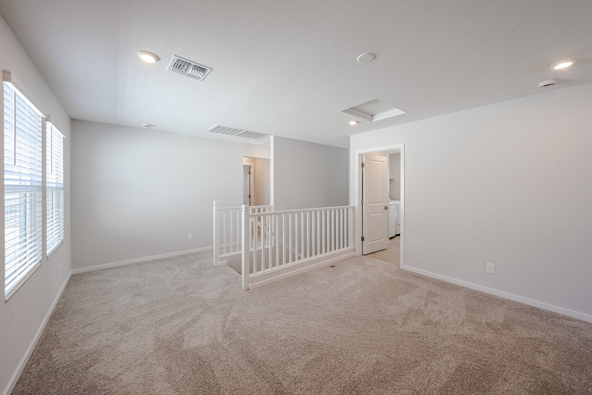 A room with a white railing and a white door.