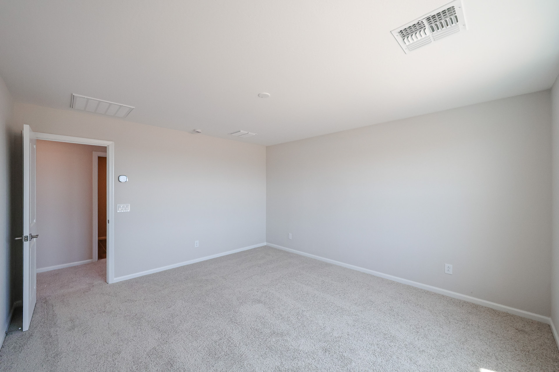 A room with a door and a wall with a vent.